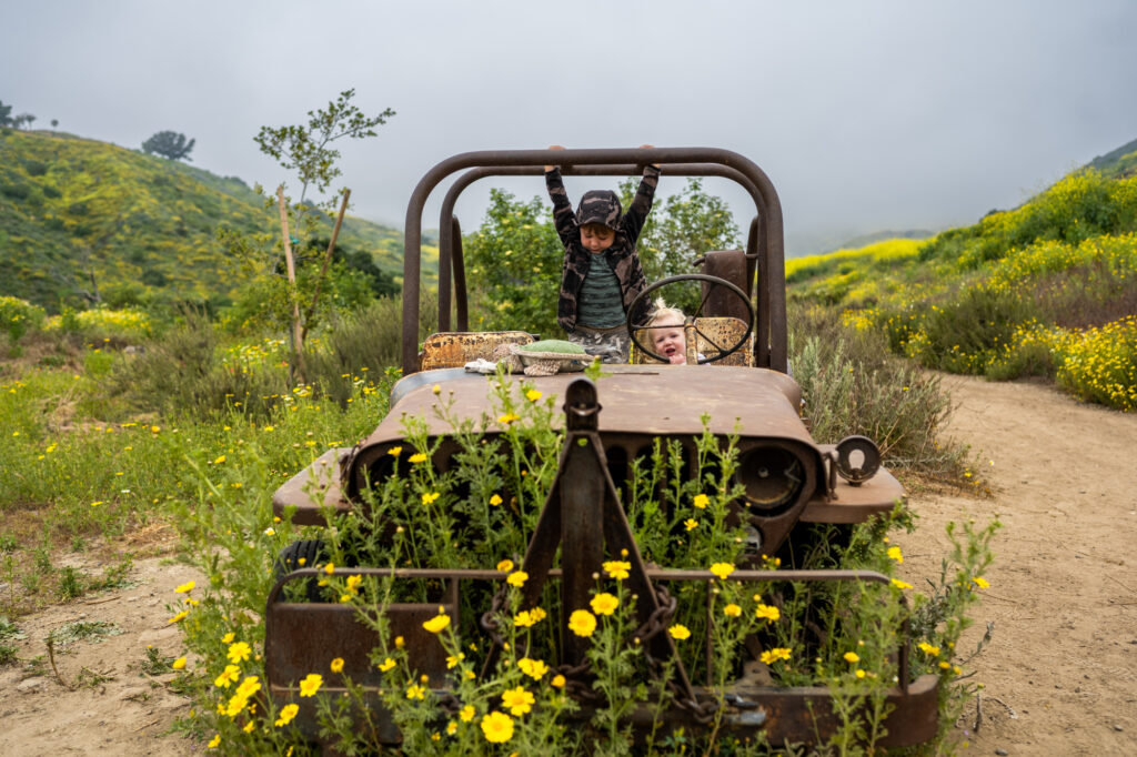 Kids playing on an abandoned Jeep in Harmon Canyon Nature Preserve Ventura during superbloom.