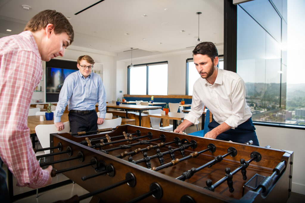 Young bankers playing foosball in the office cafeteria in Santa Monica California.