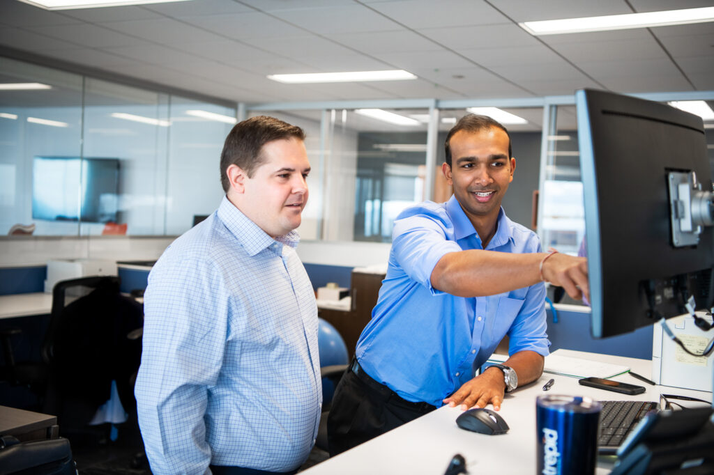 Two businessmen collaborate at the computer in a Los Angeles office.